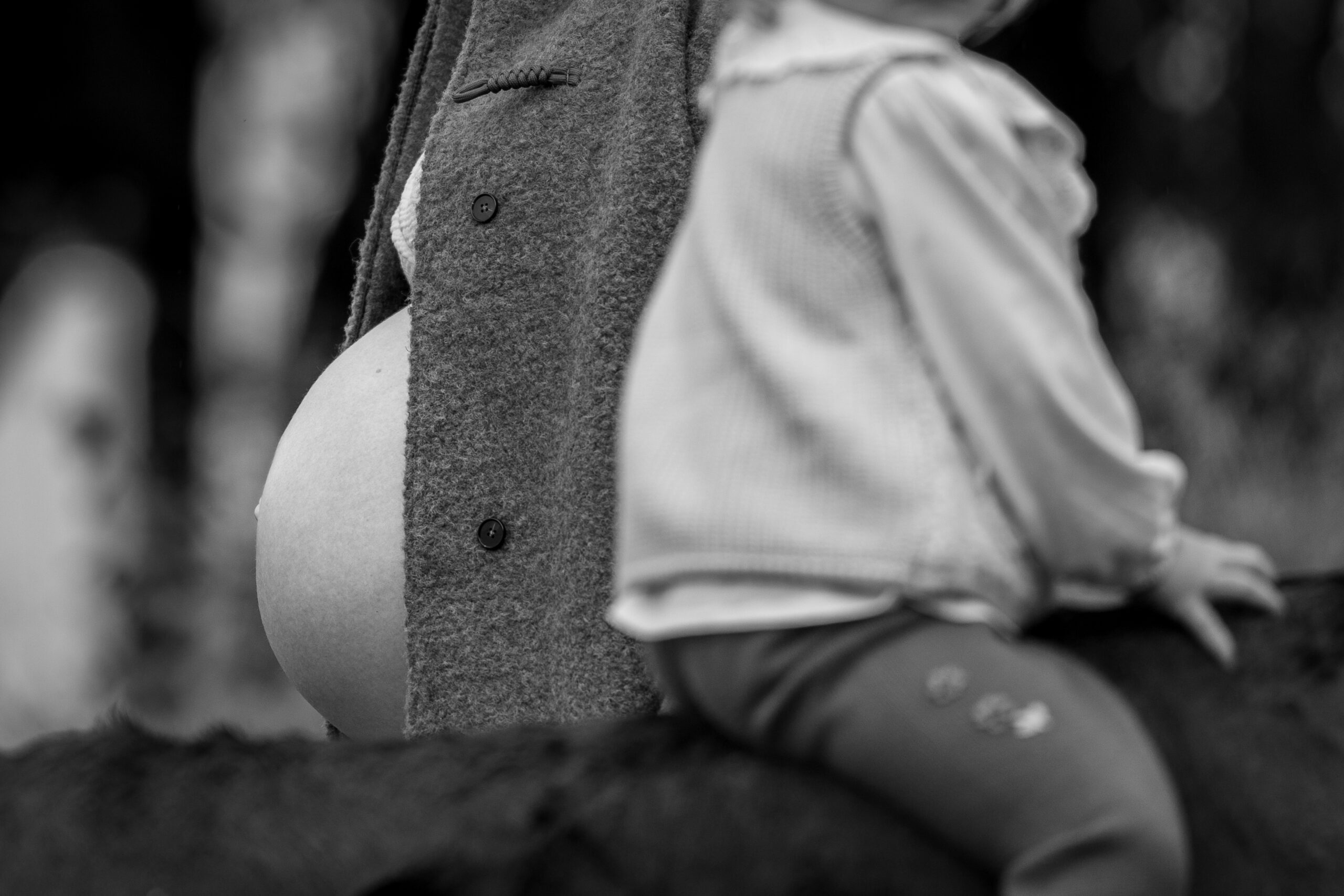 Detailaufnahme: Kind lehnt sich an den Babybauch der Mutter