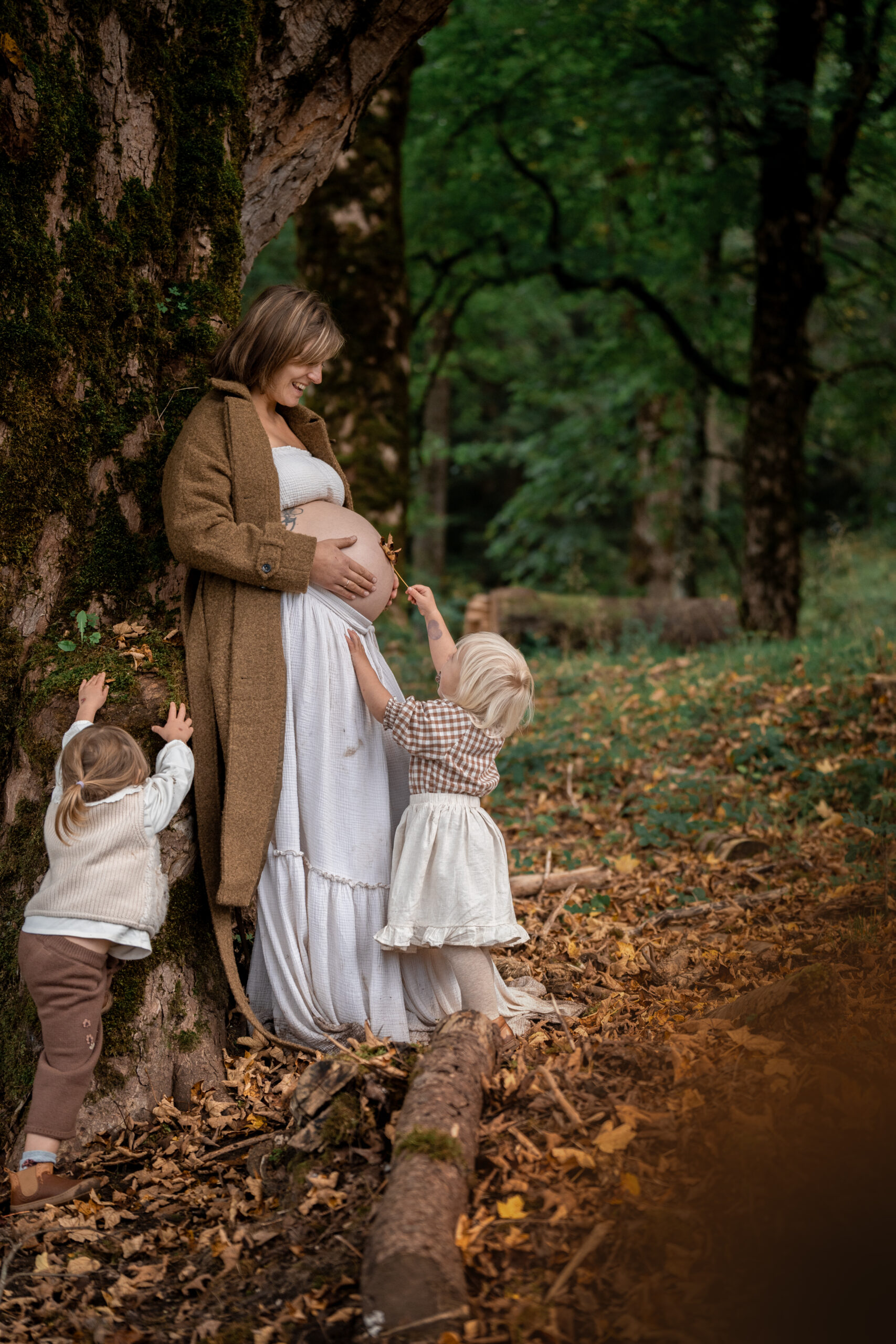 Familienmoment im Wald: Mutter mit Babybauch und zwei Kindern